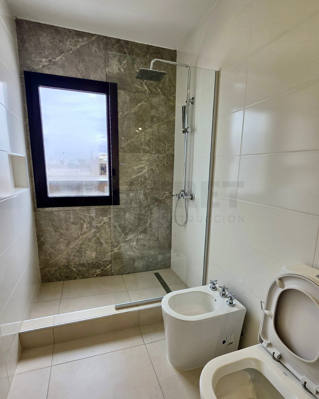 9. AM2 10 Baño principal de AM2 con mesada de granito y ducha vidriada.