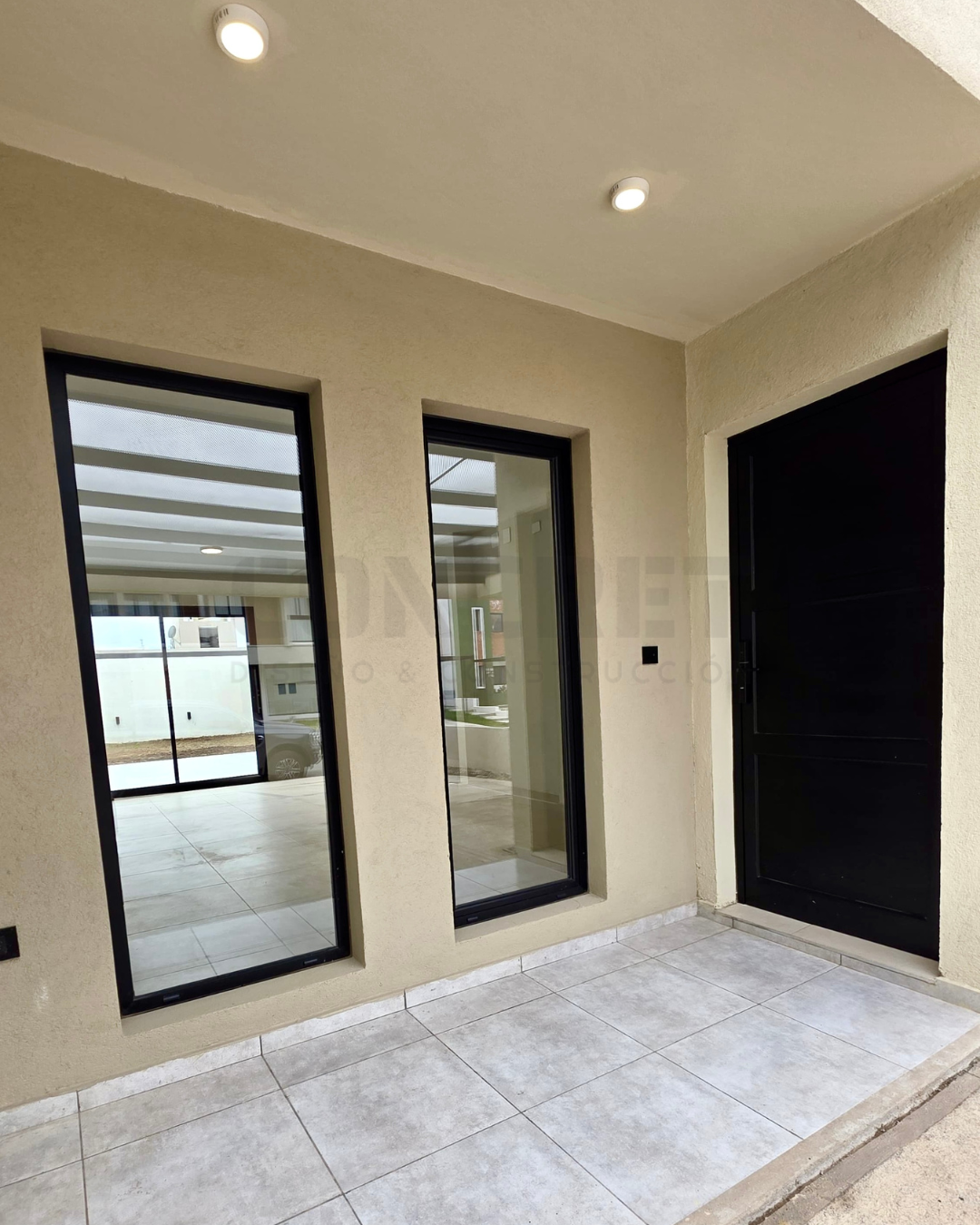 9. AM2 2 Ingreso principal de AM2 con galería techada y aberturas negras.