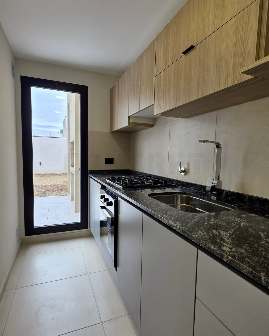 AM2 Cocina de AM2 con bajo mesada gris y alacenas en madera.